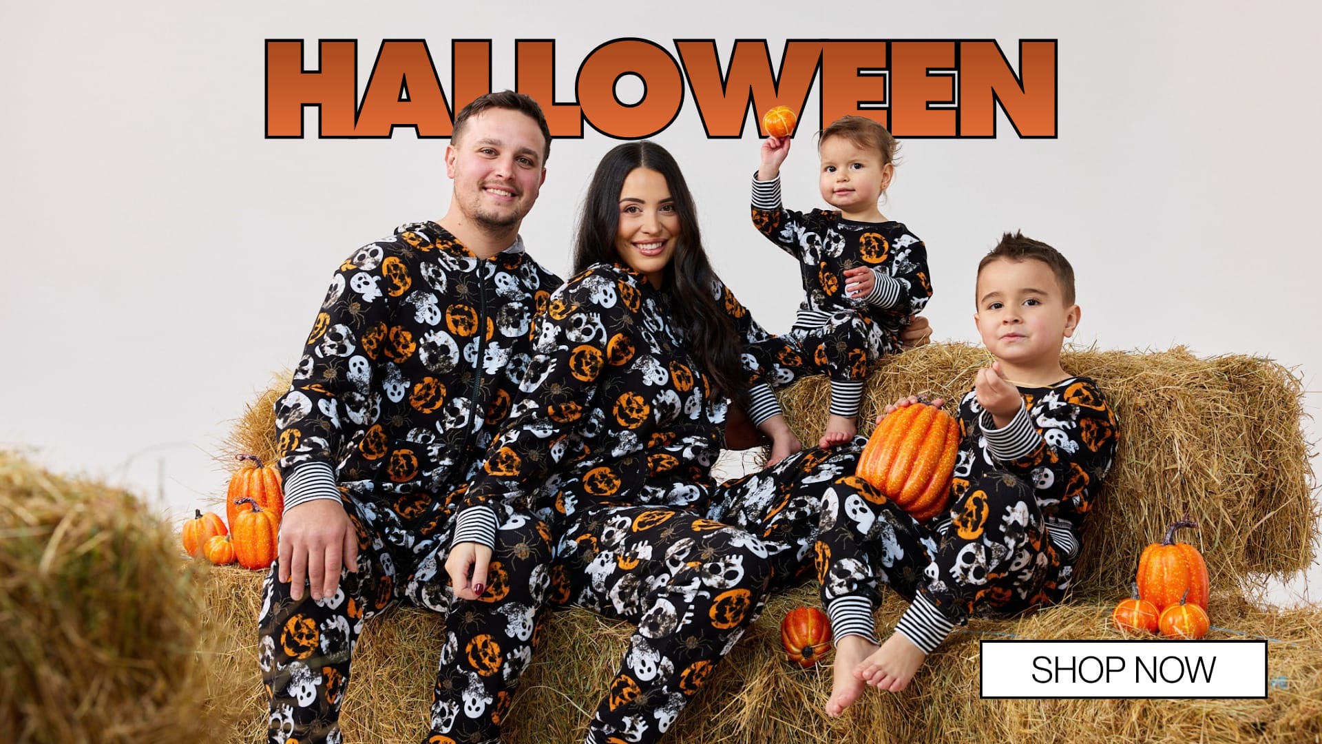 Family in matching Boo Crew Halloween pyjamas on hay bales with pumpkins